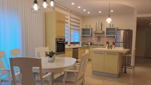 A modern kitchen with a central island, built-in appliances, and pendant lighting.