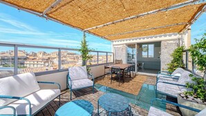 A rooftop terrace with outdoor seating, a glass table, and a view of the cityscape. - Là-Haut - Rooftop - Panorama sur la ville Parking (Montpellier)