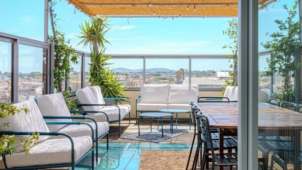 A rooftop terrace with a glass table and chairs, a sofa, and a pergola. - Là-Haut - Rooftop - Panorama sur la ville Parking (Montpellier)