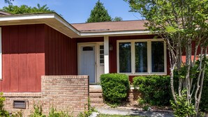 A single-story house with a red exterior, a white door, and a brick foundation. - Great home minutes from Fort Jackson (Columbia)
