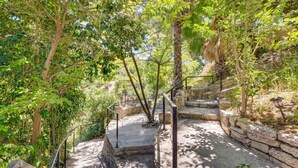 Eine steinerne Treppe, umgeben von üppigem Grün, die zu einer höheren Lage hinaufführt.
