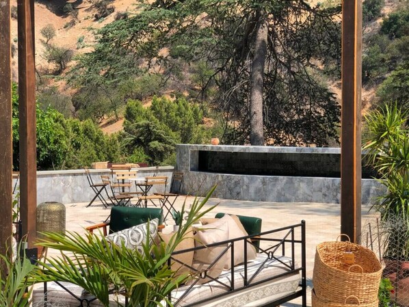 An outdoor seating area with a stone wall, wooden chairs, and green cushions.