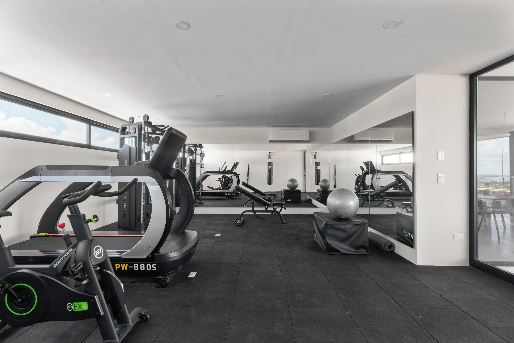 Une salle de sport moderne équipée de machines de cardio, de poids libres et de ballons d’exercice.