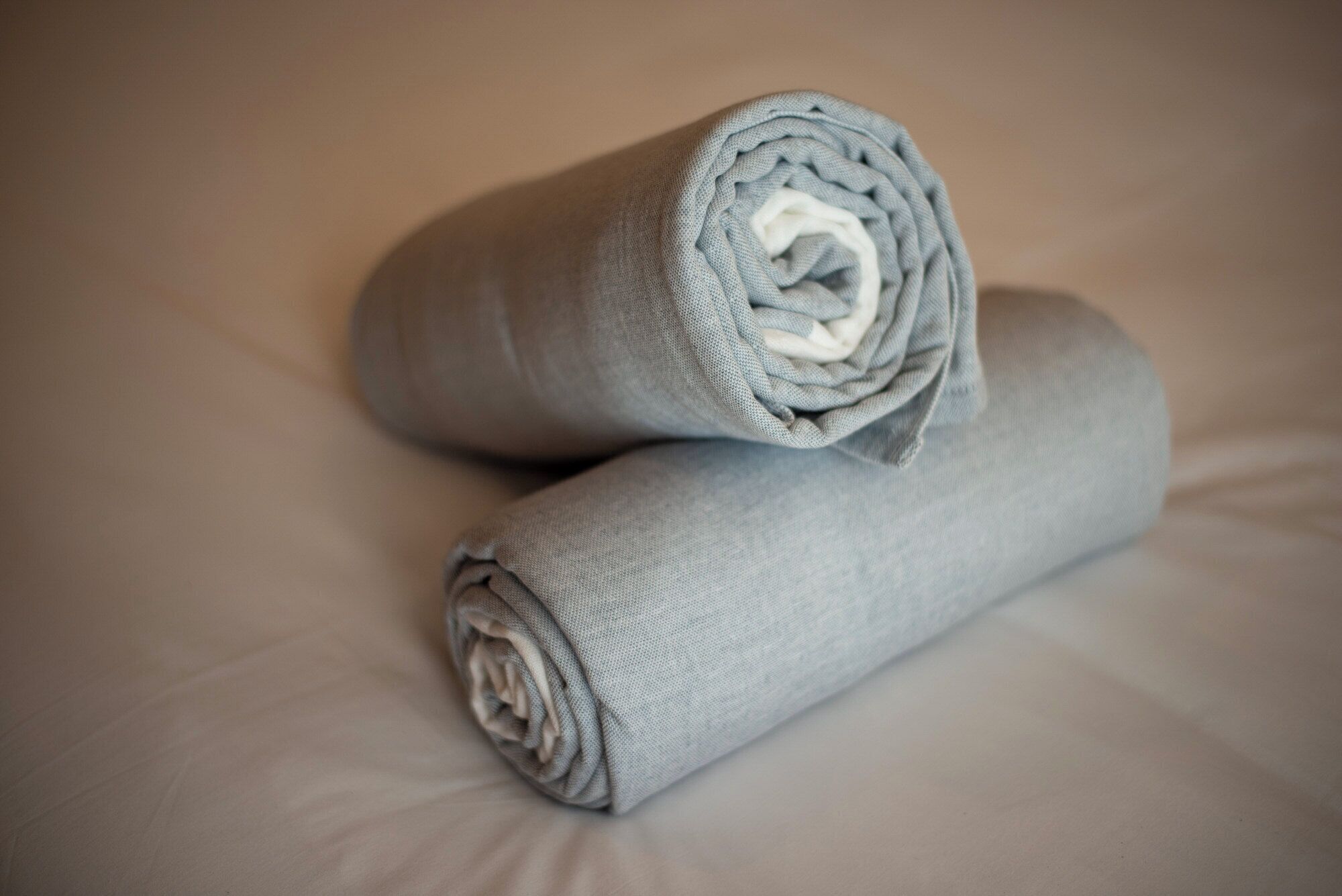 Two rolled-up towels on a bed.
