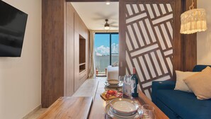 Een moderne kamer met een houten eettafel gedekt voor twee personen, een bank en uitzicht op de lucht door een schuifdeur.