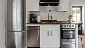 A modern kitchen with stainless steel appliances, white cabinetry, and a built-in oven. - 1 Bedroom Anchor Cottage 2 - One bedroom, one murphy bed, one sleeper sofa, with kitchenette (Allons)