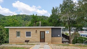 A small cabin with a stone exterior, a wooden door, and a sign indicating it is a "Cabin 2". - 1 Bedroom Anchor Cottage 2 - One bedroom, one murphy bed, one sleeper sofa, with kitchenette (Allons)