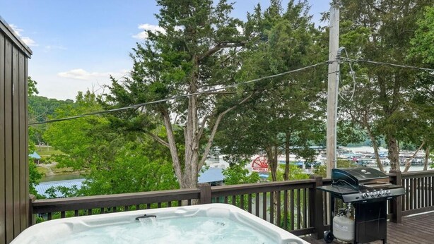 Ein Whirlpool auf einer Holzterrasse mit Blick auf einen Hafen und Bäume.