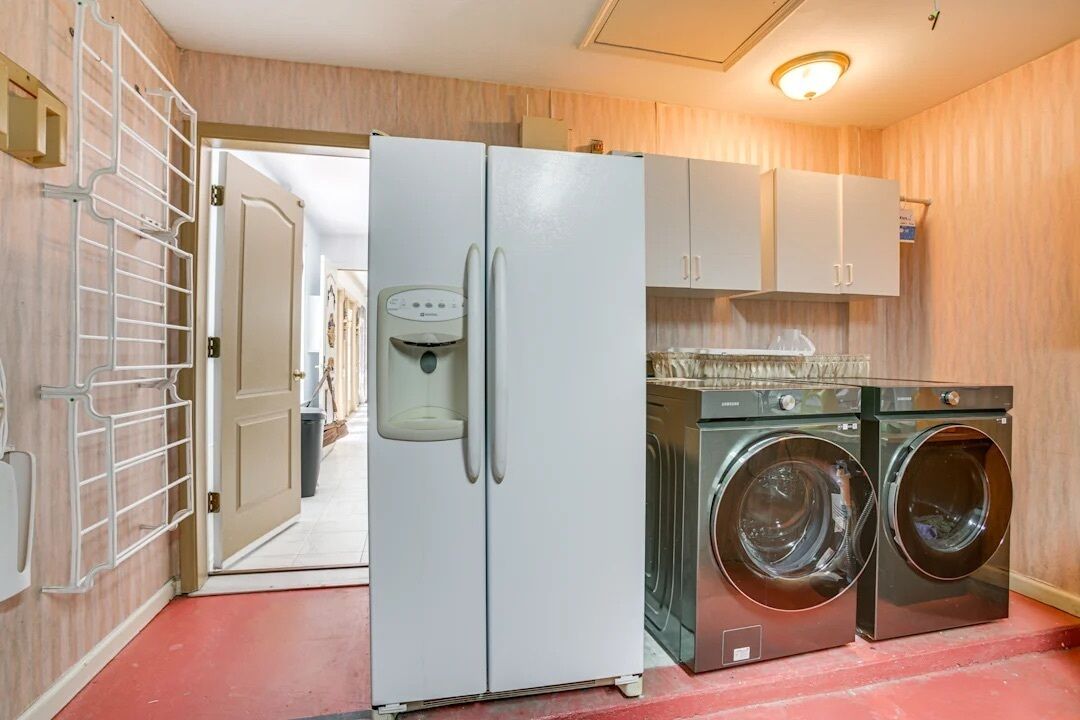 A compact kitchen with a refrigerator, washing machine, and a water dispenser.
