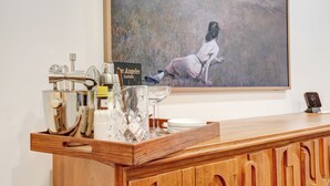 Un coin bar avec un comptoir en bois, un tableau représentant une femme dans un champ et une horloge numérique affichant 67 degrés.
