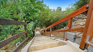 Un escalier en bois, doté d’une rampe métallique, mène le long d’un sentier rocailleux.