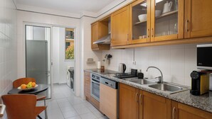 Una cocina moderna con armarios de madera, encimera de granito, lavavajillas y pileta.