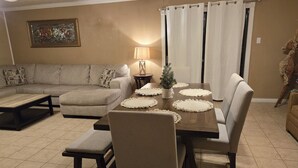 Un comedor con una mesa de madera, sillas blancas y una pequeña planta en maceta.