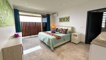 A bedroom with a bed, nightstands, a window with curtains, a wall art piece, and a balcony with a wooden fence.