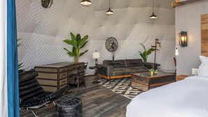 Une chambre d’hôtel confortable avec un plafond matelassé, un canapé, une table basse, un bureau et un lit.