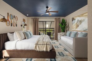 A bedroom with a bed, a sofa, a ceiling fan, and a window with curtains.