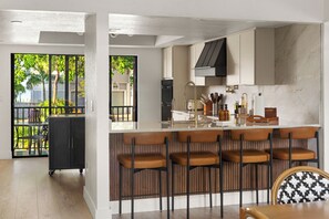 Een moderne keuken met een bar, houten barkrukken en uitzicht op het omliggende landschap.
