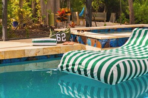 A pool area with a lounge chair, a towel, and a bag with the number 62 on it.