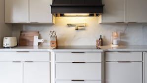 Een moderne keuken met witte kastjes, een zwarte afzuigkap en een marmeren aanrecht.