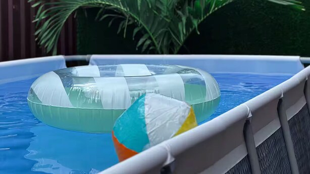 Una piscina con flotadores y una palmera al fondo.
