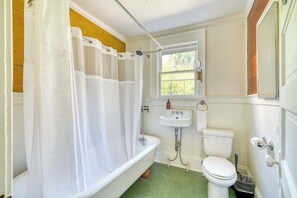 Et badeværelse med badekar, toilet og håndvask.
