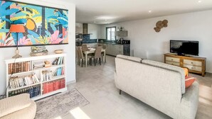 En moderne stue med en sofa, en bogreol og et farverigt maleri.