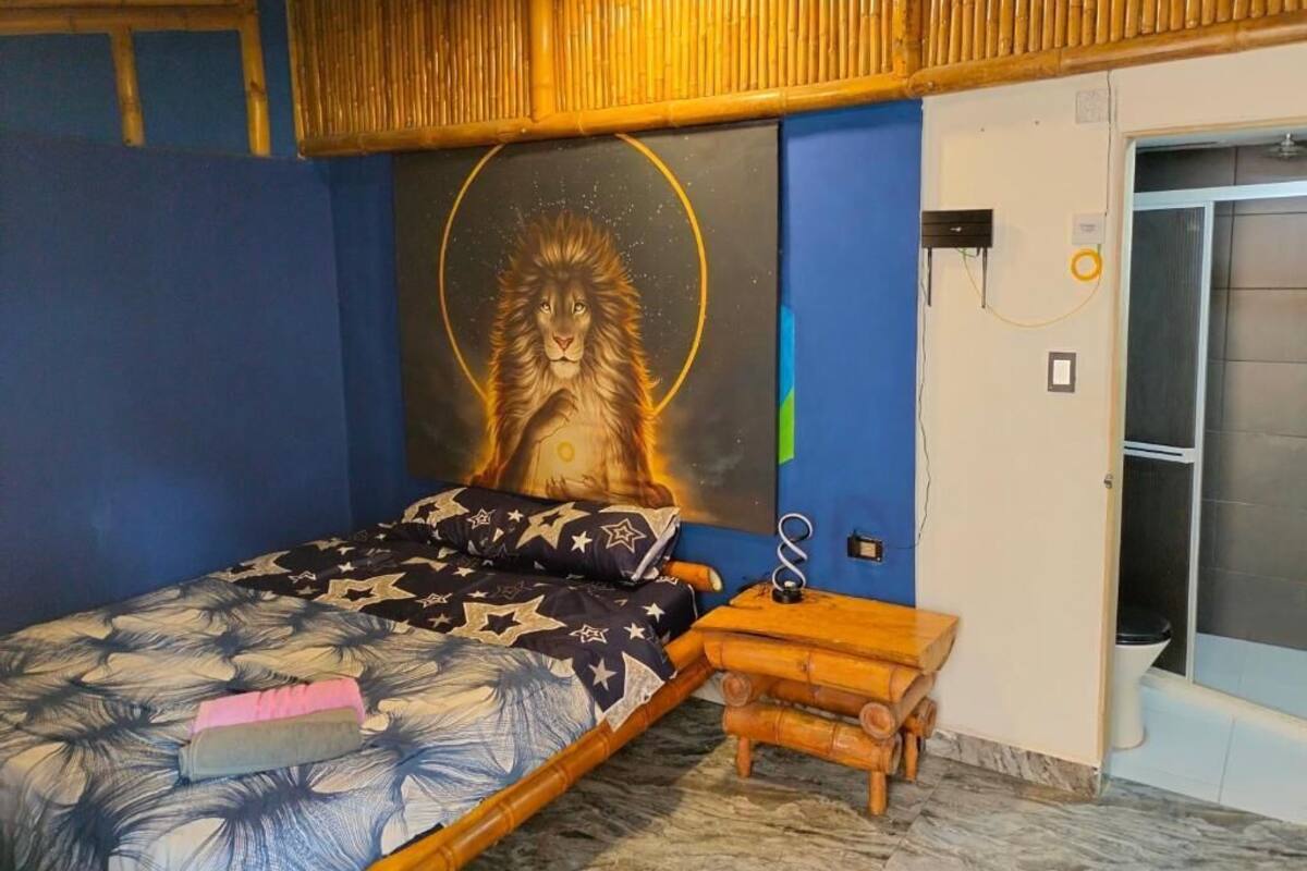 Une chambre à coucher avec un lit, un banc en bois, une fresque murale et une porte de salle de bain.