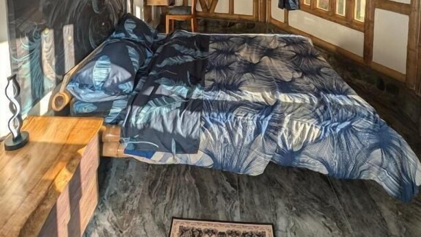 Una habitación con cama, un cuadro de un lobo, paredes de madera y techo inclinado.