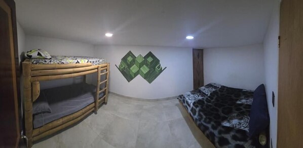 Una habitación con literas, una cama individual y un mural en la pared.