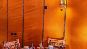 Een tent met een bed, een tafel met een rode tafelkleed en een kamerbreed tapijt.