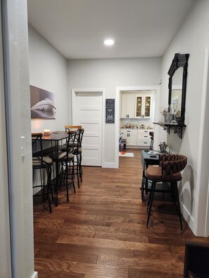 A compact kitchen with white cabinets, a dining area with wooden chairs, and a small table.