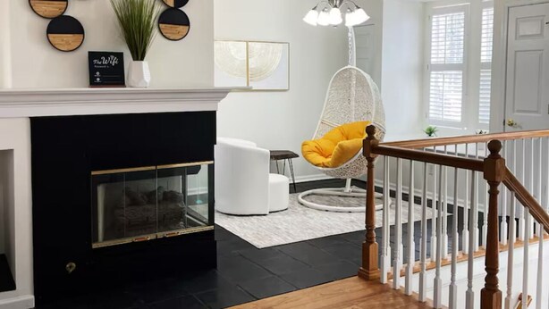 Una sala de estar moderna con chimenea, una silla colgante y una escalera.