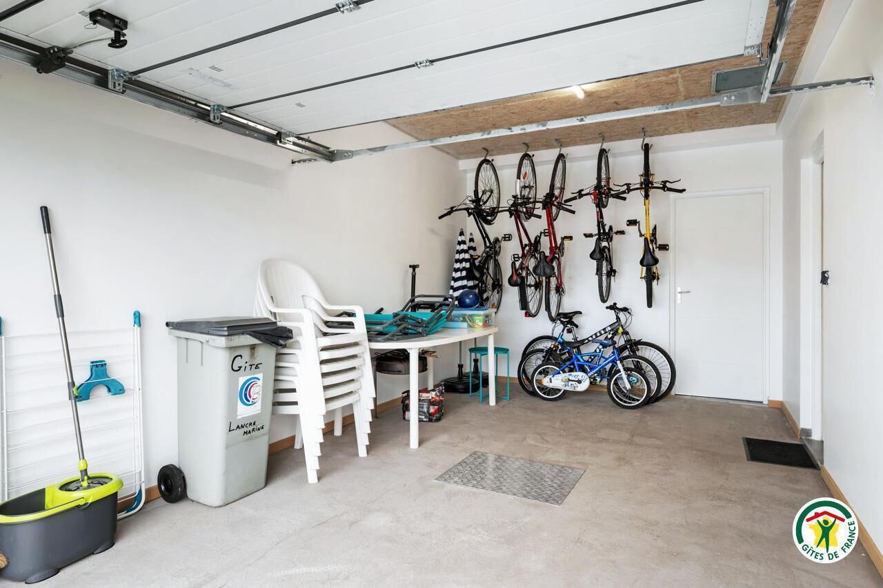 A garage with bicycles, a mop, and cleaning supplies.