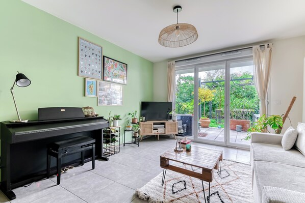 Ein Wohnzimmer mit Klavier, Flachbildfernseher, Couchtisch und Sofa.