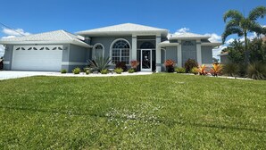 A two-story house with a garage, arched windows, and a well-maintained lawn.