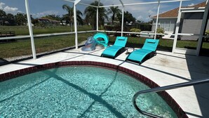 A swimming pool with clear water, surrounded by a covered area with blue lounge chairs.