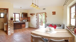 A kitchen with a brick wall, a dining area with a round table and chairs, and a view of the outdoors. - 2 bedroom lovely home in Debina (Debina)