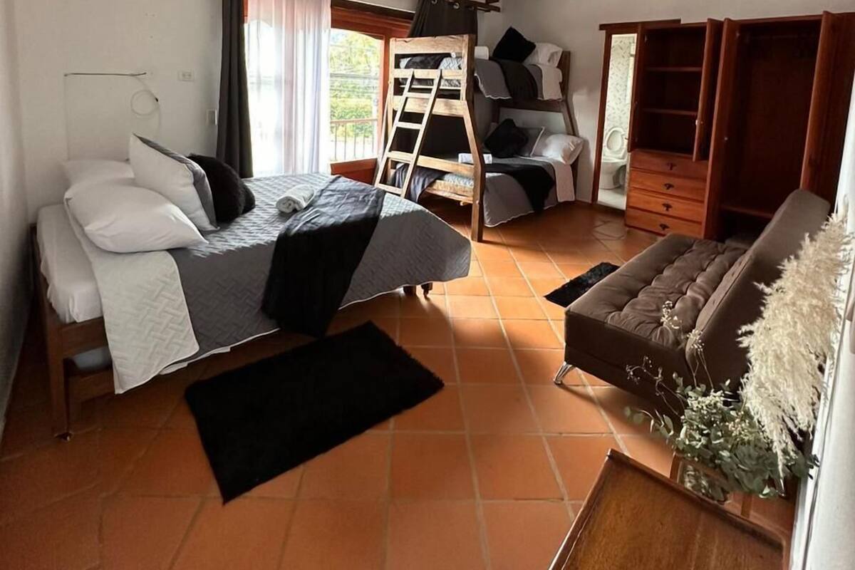 Ein Schlafzimmer mit einem Bett, einer Schlafcouch, einer Leiter und einem Holzschrank.