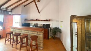 Een keuken met een bar, houten krukken en een grote kast.
