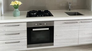 A modern kitchen with a stainless steel range hood, a built-in oven, and a sink. - Luxury Apartment with City Views in the Heart of Bondi Junction (Bondi Junction)