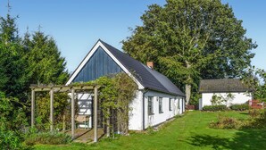 A white house with a dark roof, a wooden pergola, and a large tree in the background. - Beautiful home in Hammenhög (Hammenhög)