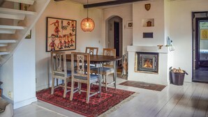 A dining area with a wooden table and chairs, a red rug, a fireplace, and a staircase. - Beautiful home in Hammenhög (Hammenhög)