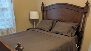 A wooden bed with a headboard, a bedside lamp, and a wooden floor. - Charming updated 1-bedroom apartment in brilliant Midland with AC (Midland)