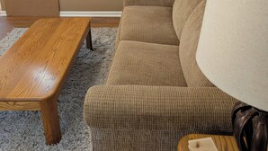 A living room with a brown sofa, a wooden coffee table, a lamp, and a framed picture on the wall. - Charming updated 1-bedroom apartment in brilliant Midland with AC (Midland)