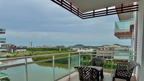 Ein Balkon mit Blick auf einen Fluss, zwei Stühle und ein Tisch.
