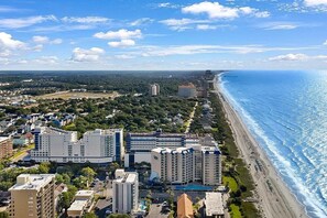 A coastal cityscape with high-rise buildings, a beach, and a clear sky.