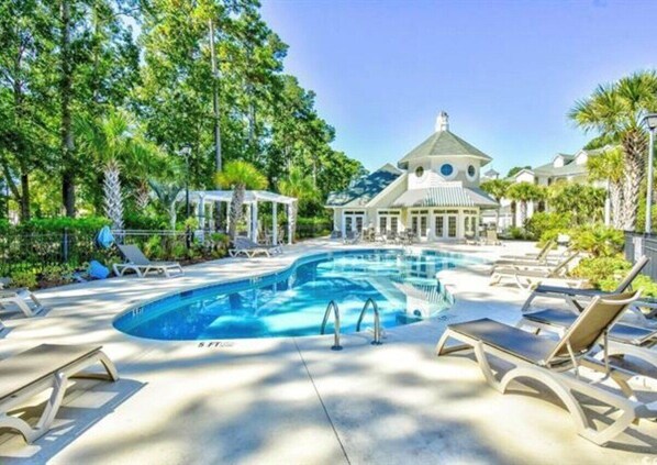 A pool area with lounge chairs, a gazebo, and a building with a dome roof.
