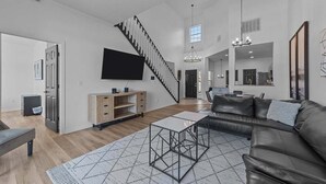 Ein geräumiges Wohnzimmer mit einer schwarzen Ledersofa, einem Couchtisch und einer Treppe, die zu einer weiteren Ebene führt.