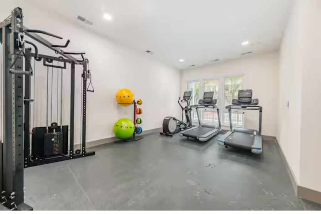 A gym with a squat rack, treadmills, a stationary bike, and exercise balls.