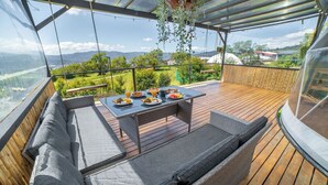 A covered outdoor seating area with a table set for a meal, overlooking a scenic landscape. - Tocuma Glamping (San Rafael)